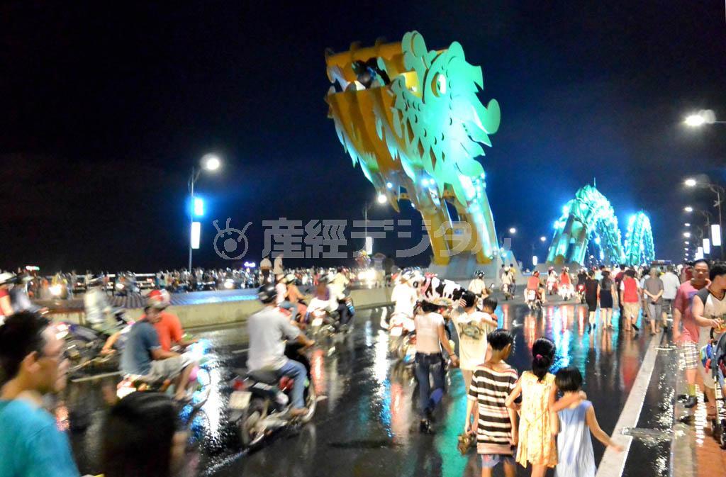 ドラゴンブリッジの通行止めが解除され、びしょ濡れになった道路をバイクが行き交う＝ベトナム中部のダナン（長浜明宏撮影）