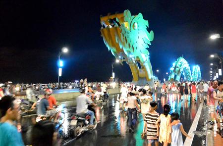 ドラゴンブリッジの通行止めが解除され、びしょ濡れになった道路をバイクが行き交う＝ベトナム中部のダナン（長浜明宏撮影）