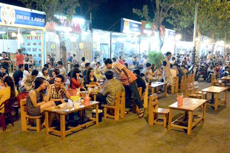 路上にテーブルと椅子を出したドラゴンブリッジ周辺の飲食店は大変なにぎわいを見せていた＝ベトナム中部のダナン