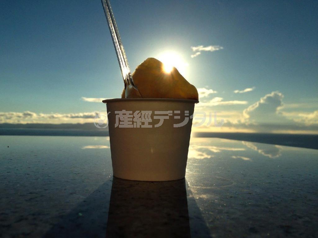 【読者写真（神奈川県横須賀市、福井純平さん）】よく見るとアイスクリーム。山から太陽が昇っていくかのような壮大さを感じる作品で、驚きました。アイスを置いた床は写り込みのある場所を選んであり、写った空が浮いているようにも見えます。カップの手前が黒く潰れていないので濃い部分から薄い部分まで立体感もあり、カップから手前にのびている影も効果的で、とても計算された作品です。すばらしいです（提供写真）