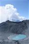 御嶽山（おんたけさん、３０６７メートル）の二の池。美しい水色の湖にも火山灰が降り注いでいた。後方は白煙を上げる御嶽山＝２０１４年９月２８日午前、長野県側の御嶽山山頂付近（本社チャーターヘリから、大山文兄撮影）