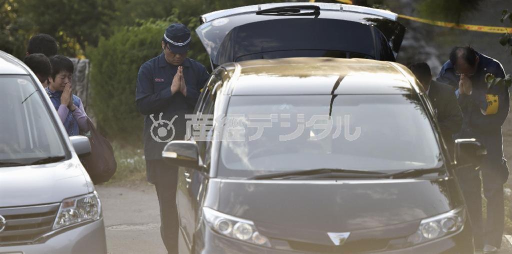 御嶽山（おんたけさん、３０６７メートル）噴火による犠牲者のひつぎを遺体安置所から車に運び込み、手を合わせる関係者。火山活動による犠牲者数では戦後最悪となった＝２０１４年１０月１日午後３時５５分、長野県木曽郡木曽町（共同）