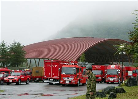 深い霧に覆われた御嶽山のふもとで待機する消防車両。雨のため捜索活動は中止となった＝３日午前、長野県王滝村