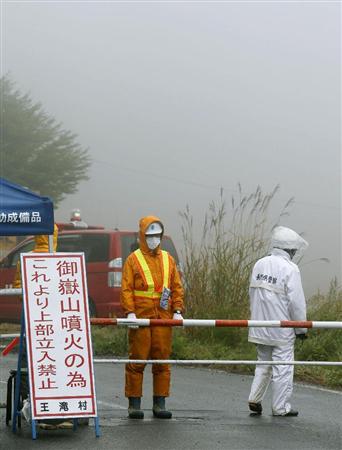 御嶽山の登山口へ続く道を警備する警察官ら。雨のため捜索活動は中止になった＝３日午前、長野県王滝村