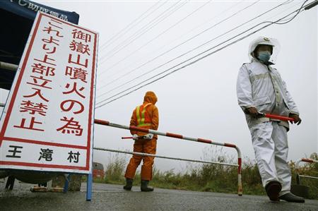 御嶽山の登山口へ続く道を警備する警察官ら。雨のため捜索活動は中止になった＝３日午前、長野県王滝村