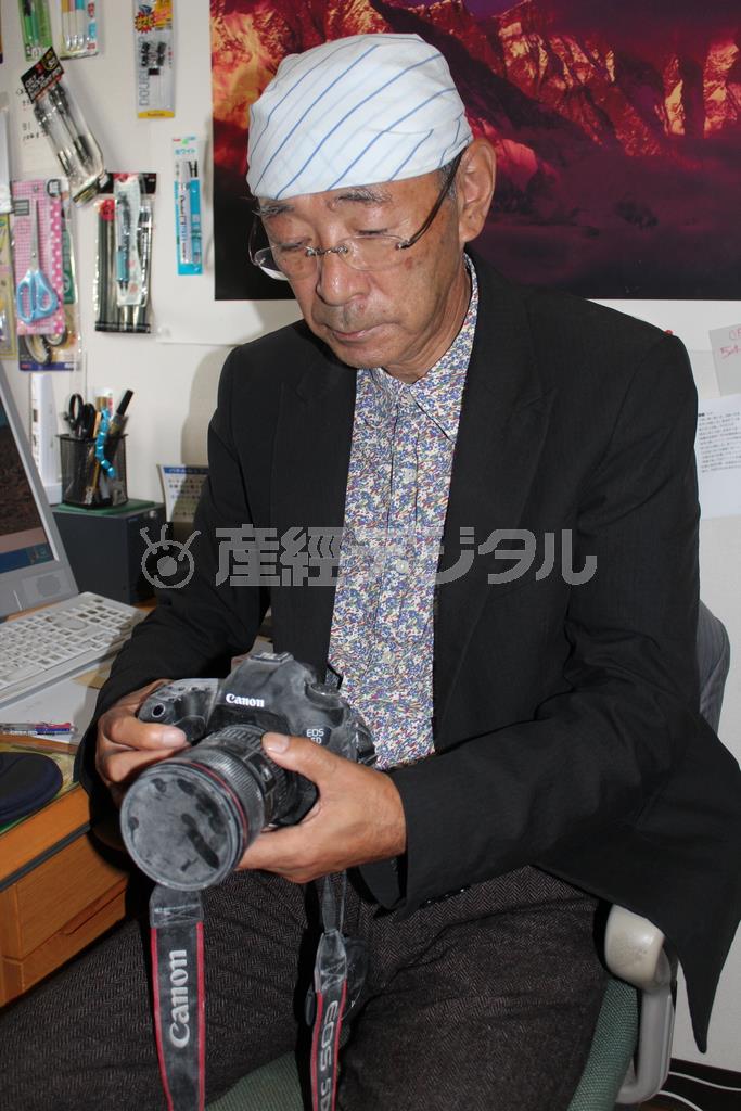 火山灰がこびりついた愛用のカメラを見つめ、当時の状況を語る津野祐次さん＝２０１４年１０月２日、長野県伊那市（玉崎栄次撮影）