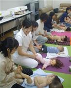 助産師の実演にあわせて子供をマッサージする母親ら。気持ちよさそうに寝入ってしまう子供もいた＝大阪市中央区の国立病院機構大阪医療センター
