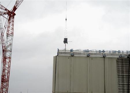 クレーンでつり下ろした機器で建屋カバーの屋根部分に穴を開ける作業＝２２日午前、福島第１原発１号機（東京電力提供）