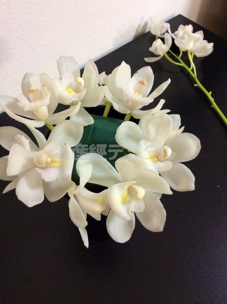 （手順２）オアシスをセットした花器に茎から切り分けたシンビジウムの花を縁部分を囲うように１０～１２輪くらい挿す＝２０１４年１０月２０日（花千代さん提供）
