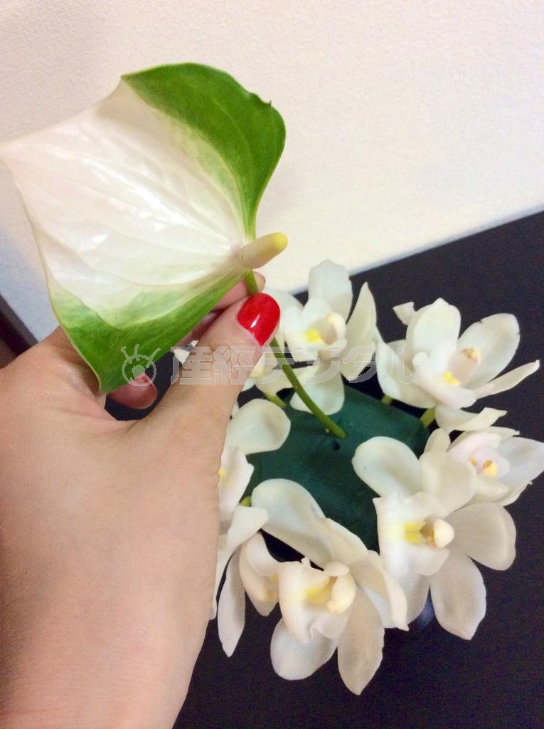 続いて白グリーンの変わり咲きのアンスリウムを一輪、バランスをみてあしらう。このときアンスリウムは中央でなく左寄りや右寄りでもよい。自分なりのバランスでＯＫ＝２０１４年１０月２０日（花千代さん提供）