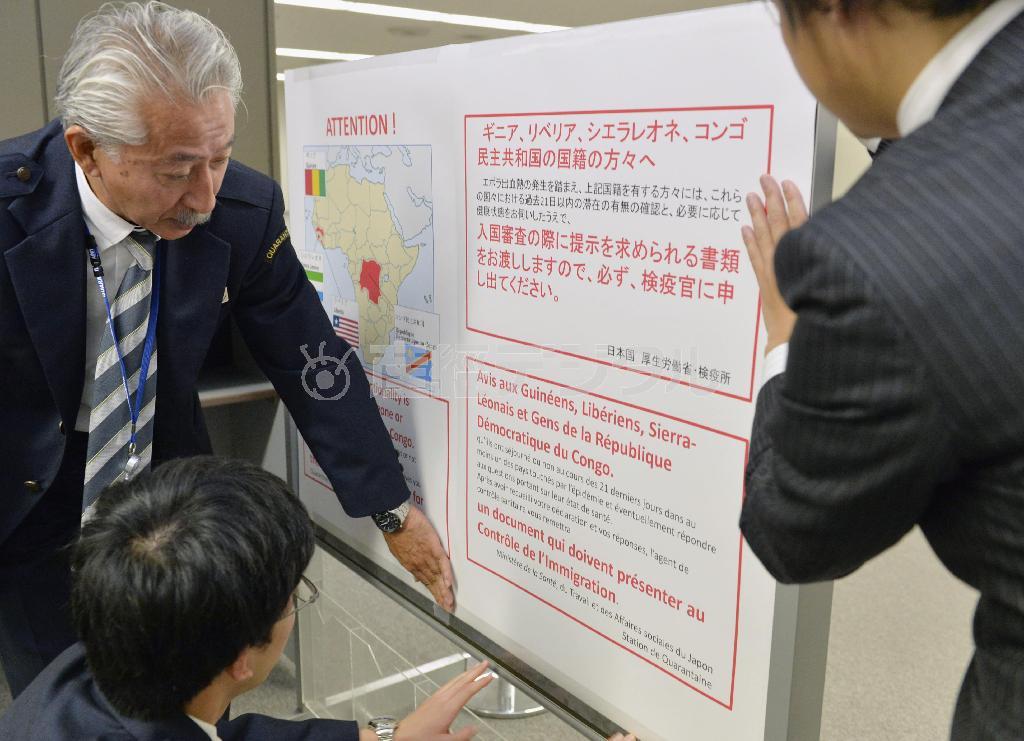成田空港で、入国者に向けたエボラ出血熱対策のポスターを張る検疫所職員＝２０１４年１０月２８日、千葉県成田市（共同）