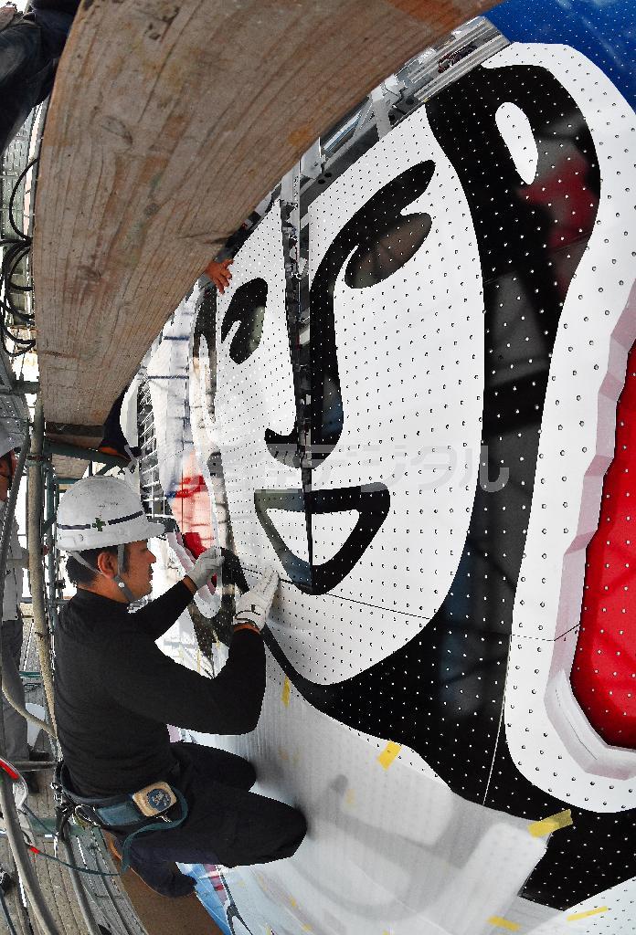 工事幕に覆われた現場では、分割された６代目の顔のパーツが慎重に取り付けられていた＝２０１４年１０月１日、大阪市中央区（竹川禎一郎撮影、魚眼レンズ使用）