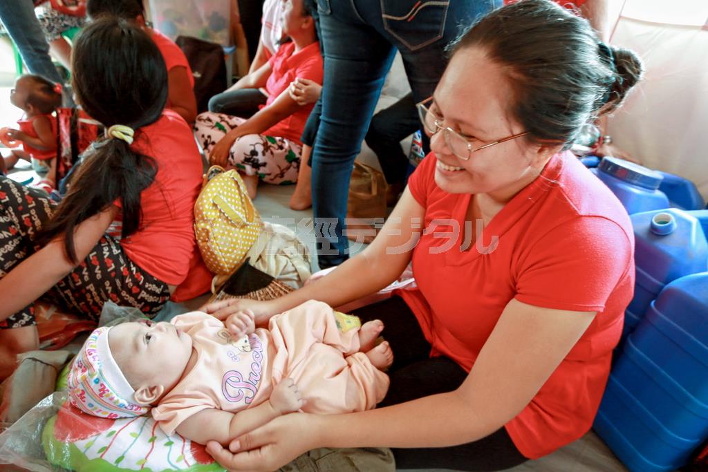 台風の６日後に生まれた男の子をあやすお母さん。ワールド・ビジョン・ジャパンは災害時でもお母さんが安心して授乳や育児ができるスペースを設置している＝２０１３年１１月１４日、フィリピン（ワールド・ビジョン・ジャパン撮影）