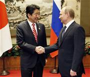 会談を前にロシアのプーチン大統領（右）と握手を交わす安倍首相＝９日、北京（共同）