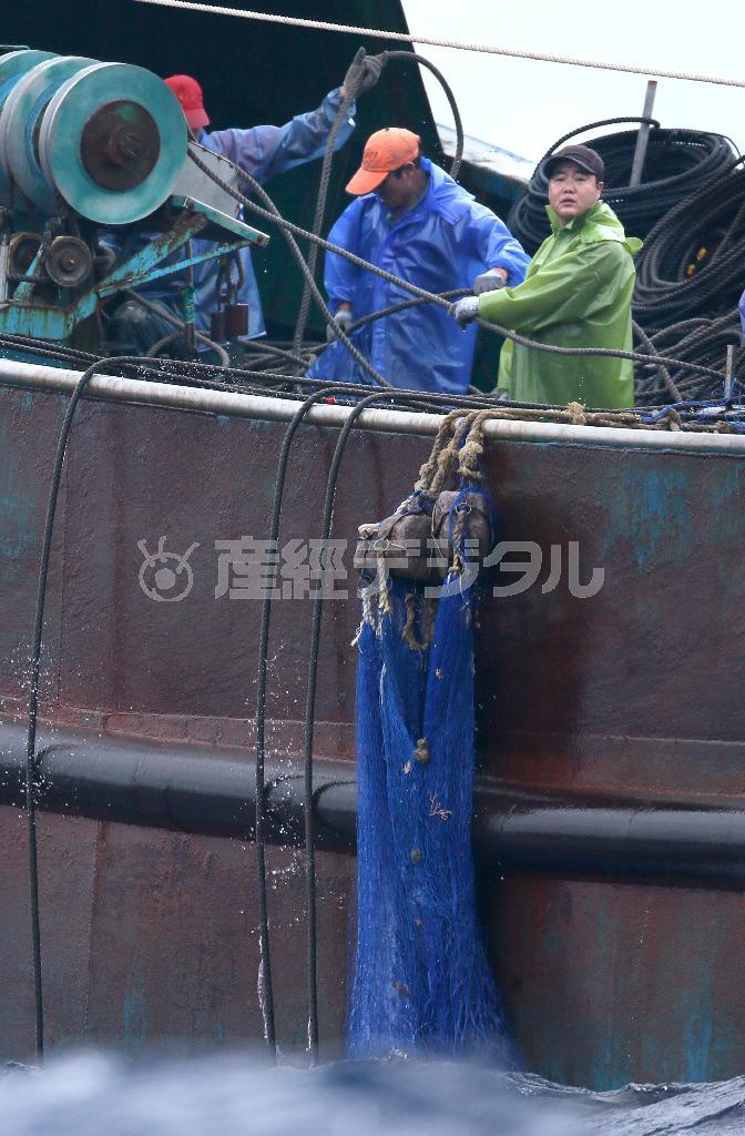 巡視船の前で悠々と網を巻き上げる中国漁船の船員＝２０１４年１１月９日、東京都の小笠原沖（大山文兄撮影）