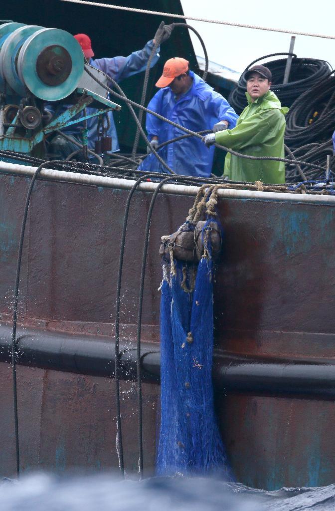 海上保安庁の巡視船「するが」を前に、サンゴ密漁用とみられる網を引き上げる中国漁船の乗組員＝９日午前、小笠原諸島・父島南の領海内（大山文兄撮影）