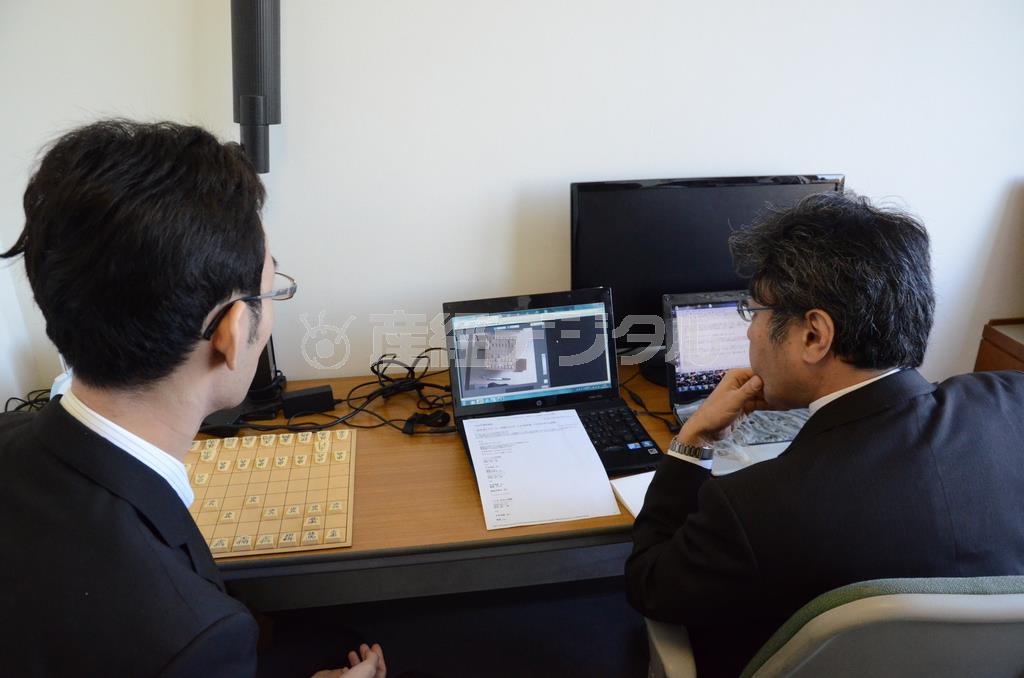 実際に行われている対局のテレビ映像を見ながら、スマートフォンに刻々、棋譜を配信する中継記者たち＝２０１４年１１月１３日、東京都渋谷区千駄ケ谷（原圭介撮影）