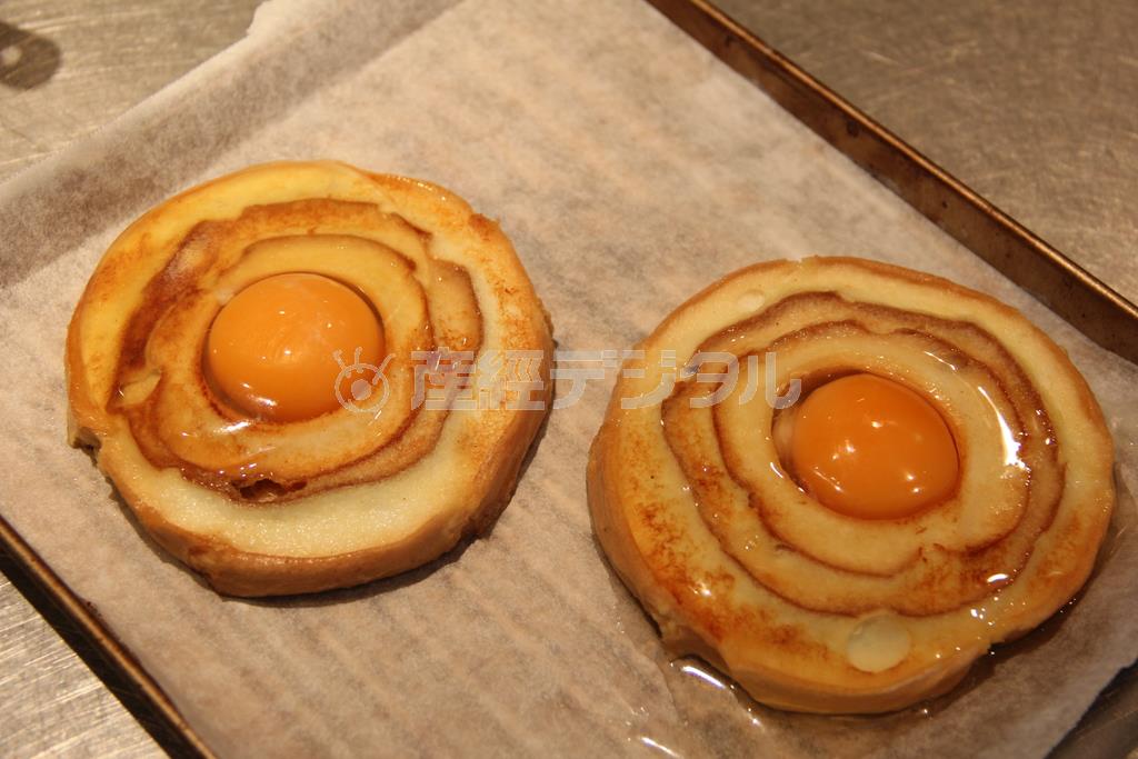 麩のクロックマダム（作り方２）＿＿フライパンにバターを熱し、（作り方１：調理した車麩（くるまふ））の両面を香ばしく焼いてからトースターの天板に移す。中央に卵を割り入れ、ハムをのせ、ホワイトソースをかけて、さらにチーズをのせて、１０分ほど焼く。