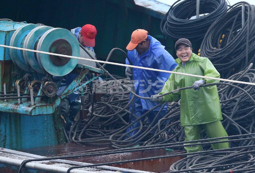 海上保安庁の巡視船に発見されてもなぜか笑顔で網を回収する中国漁船の乗組員＝２０１４年１１月９日、小笠原諸島・父島（東京都小笠原村）の南１６キロの領海内（大山文兄撮影）