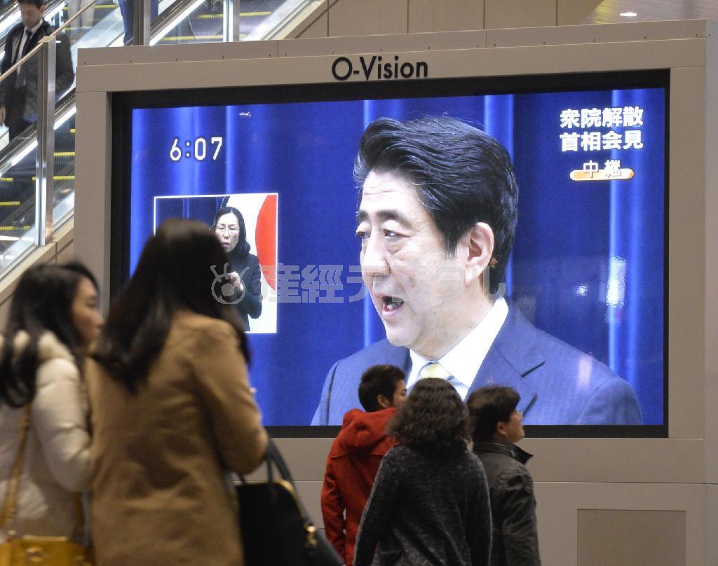 街頭のテレビで安倍晋三（しんぞう）首相の会見に見入る人たち＝２０１４年１１月２１日午後６時過ぎ、大阪市北区（安元雄太撮影）