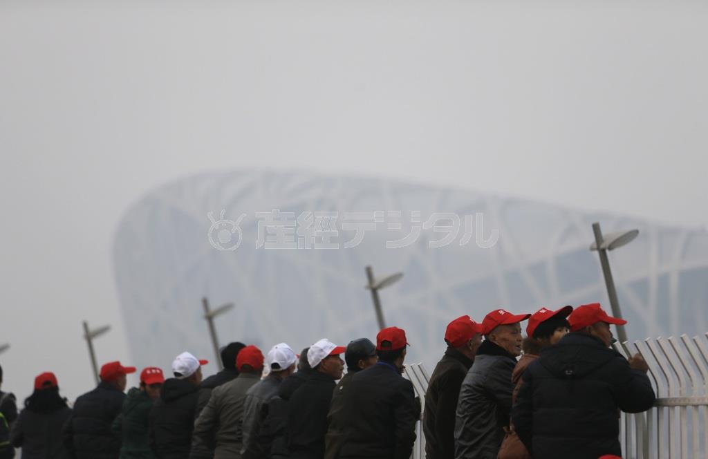 鳥の巣の通称で知られる北京の国家体育場を訪れた観光客ら。大気汚染対策が解除され、再び北京の空をスモッグが覆った＝２０１４年１１月２０日、中国・首都北京市朝陽区（ロイター）