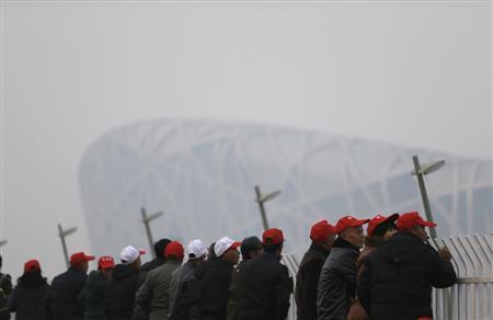 鳥の巣の通称で知られる北京の国家体育場を訪れた観光客ら。大気汚染対策が解除され、再び北京の空をスモッグが覆った＝２０１４年１１月２０日、中国・首都北京市朝陽区（ロイター）