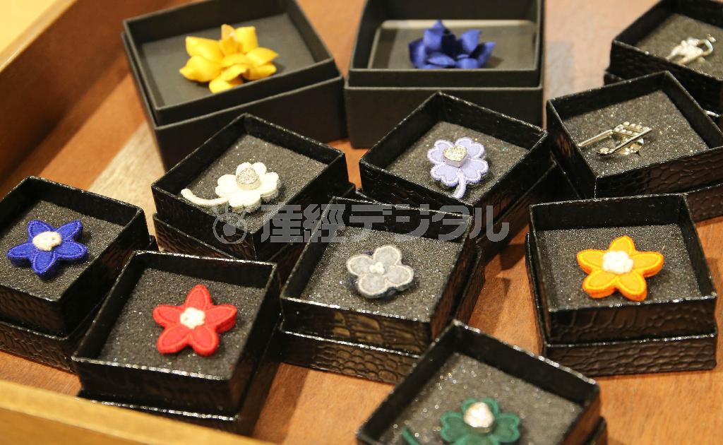 ジャケットの襟に刺すピンズの数々（２５００円から）。造花に花のアップリケ、クリスタルにシルバー仕立てのものまで。男女問わずジャケットにワンポイントを＝２０１４年１２月３日、東京都中央区銀座（宮崎裕士撮影）