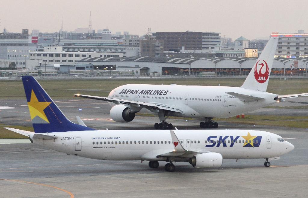 福岡空港に着陸したスカイマーク機（手前）と離陸を待つ日本航空機＝２１日午後