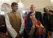 記者会見の会場に到着したマララ・ユスフザイさん（右手前）と共同受賞者のカイラシュ・サトヤルティさん（左）。後方はノルウェー・ノーベル賞委員会のトールビョルン・ヤーグラン委員長＝２０１４年１２月９日、ノルウェー・首都オスロ（ロイター）