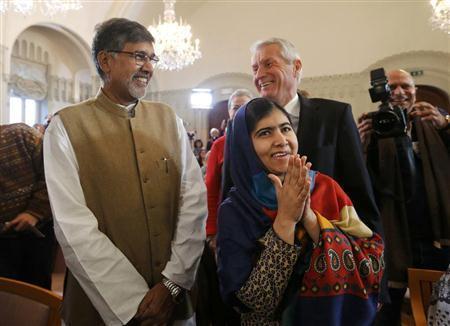 記者会見の会場に到着したマララ・ユスフザイさん（右手前）と共同受賞者のカイラシュ・サトヤルティさん（左）。後方はノルウェー・ノーベル賞委員会のトールビョルン・ヤーグラン委員長＝２０１４年１２月９日、ノルウェー・首都オスロ（ロイター）