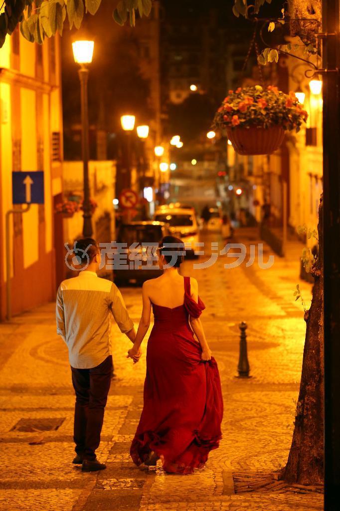 ポルトガルの植民地だったという歴史が分かるような石畳にオレンジ色の外灯、偶然通りかかったウエディングの衣装を着たカップルの後ろ姿です。頭上の花や左側の矢印のサインもアクセントになるかな？と思い、一瞬で構図を決めました＝２０１４年１１月２６日、中国・マオカ（須藤夕子さん撮影）