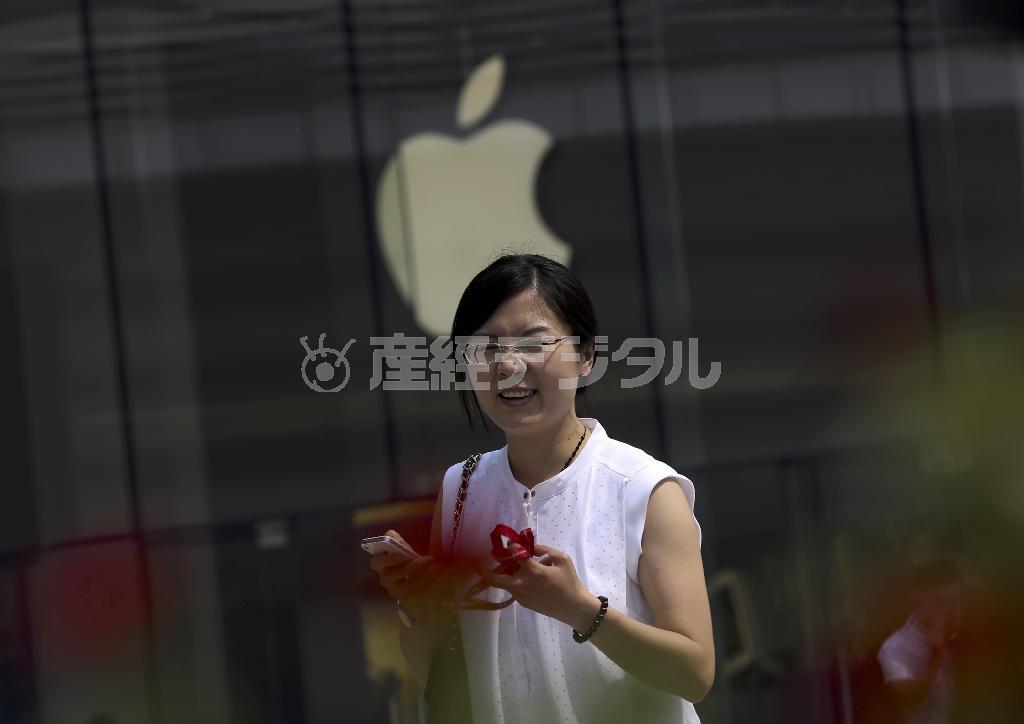 中国・首都北京市のアップル・ストア前で携帯端末を操作する女性＝２０１４年９月３０日（ＡＰ）