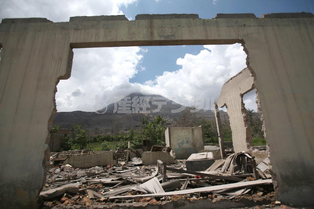 建物の残骸が額縁となって背後に見える山を映し出す。インドネシア・スマトラ島北部にあるシマチェム村では、４００年の眠りから覚めた活火山のシナブン山が２０１０年に噴火。２万２０００人が半径約３キロ圏内から避難し、村は廃墟となった。シナブン山はインドネシア国内に約１３０ある活火山のうちの一つで、今も断続的に噴火を続けている＝２０１４年１１月２２日（ＡＰ）