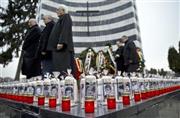 チャウシェスク独裁政権崩壊のきっかけとなった軍のデモ銃撃事件から２５年を迎えた１２月１７日、ルーマニア西部ティミショアラの墓地では、礼拝のために犠牲者の顔写真とろうそくが供えられた＝２０１４年（ＡＰ）