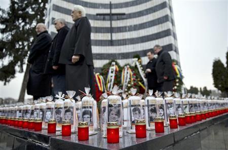 チャウシェスク独裁政権崩壊のきっかけとなった軍のデモ銃撃事件から２５年を迎えた１２月１７日、ルーマニア西部ティミショアラの墓地では、礼拝のために犠牲者の顔写真とろうそくが供えられた＝２０１４年（ＡＰ）