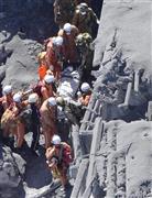 長野、岐阜両県にまたがる御嶽山（３０６７メートル）が９月２７日に噴火、山頂付近にいた多くの登山者が巻き込まれ、５７人が死亡、６人が行方不明になる戦後最悪の火山災害となった。写真は山頂付近の山小屋の脇で、登山者の救出活動を行う救助隊員ら＝２０１４年９月２８日午前１１時５３分（本社ヘリから、甘利慈撮影）