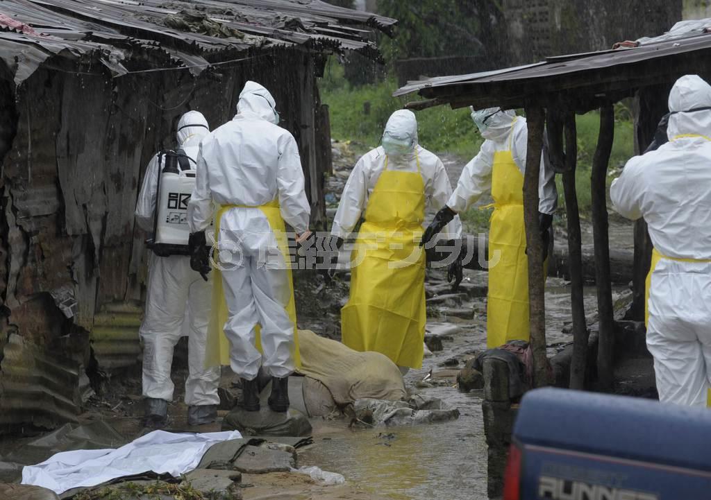 リベリアの首都モンロビアで８月１７日、エボラ出血熱による犠牲者の遺体を運び出す衛生当局者たち＝２０１４年（ロイター）