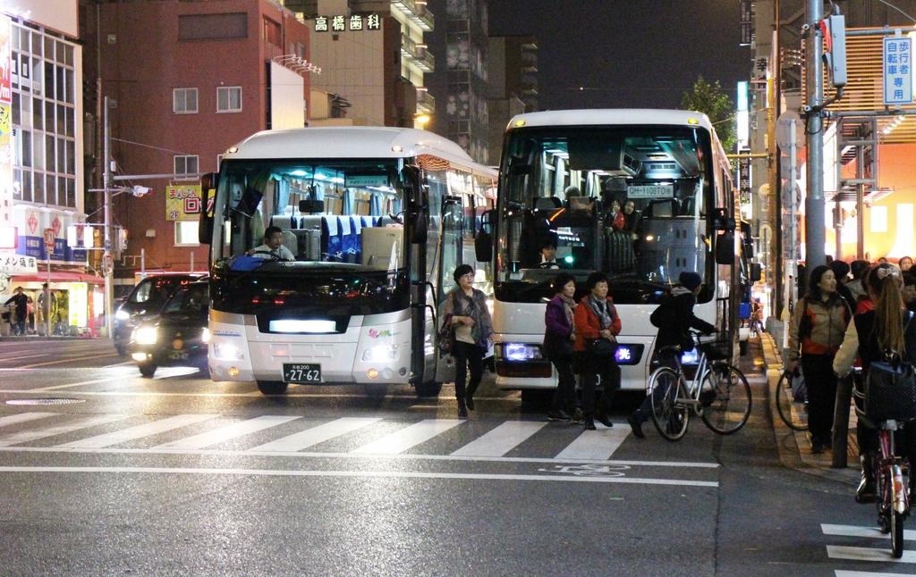 観光バスで混雑するミナミ・道頓堀近くの日本橋。多重駐車に加え、間をすり抜けようとする自転車の危険な走行も問題になっている＝大阪市中央区