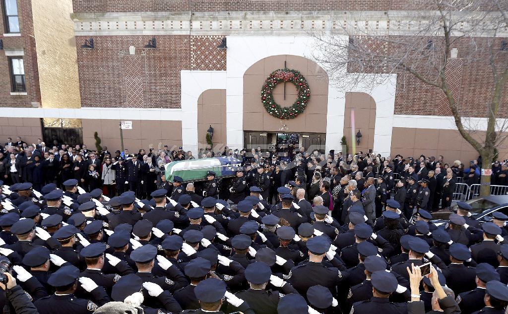 葬儀後に教会から運び出される警官、ラファエル・ラモス氏のひつぎ。全米各地から集結した警官約２万５０００人が敬礼で見送った＝２０１４年１２月２７日、米ニューヨーク・クイーンズ地区（ＡＰ）