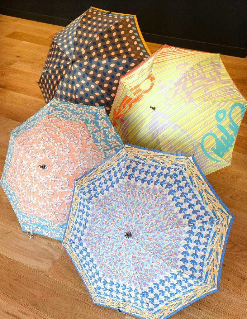 ３月から発売する傘。右奥はスペインのシャッターに書かれた落書きがモチーフの１枚張り（１万４０４０円）、左奥の水玉は色違いもあり（８６４０円）、手前２品はＵＶカットの遮光機能つき日傘（１万８００円）。いずれも販売予定価格＝２０１４年１２月１８日、東京都港区（寺河内美奈撮影）