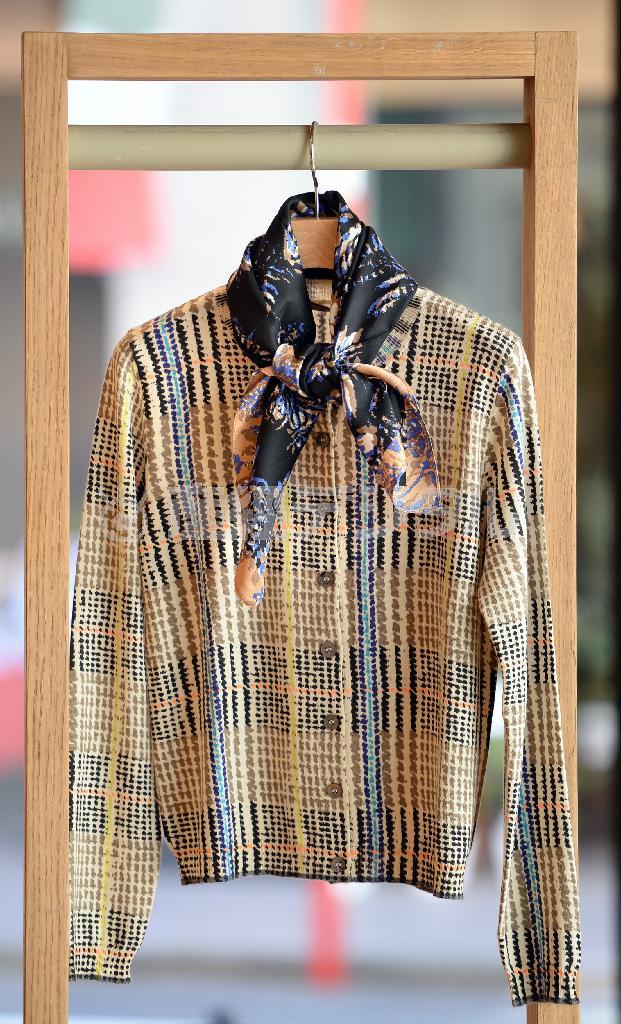 メリノウールのカーディガンは縫製の都合でイタリアで製造（５万８８６０円）。首に花柄のシルクスカーフ（１万８３６０円）を巻いてアクセントを＝２０１４年１２月１８日、東京都港区（寺河内美奈撮影）