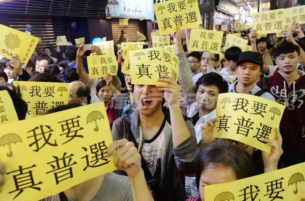 「真の普通選挙が必要だ」と書かれた黄色い紙を掲げるデモ参加者＝２０１４年１１月、中国・香港（共同）