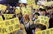 「真の普通選挙が必要だ」と書かれた黄色い紙を掲げるデモ参加者＝２０１４年１１月、中国・香港（共同）