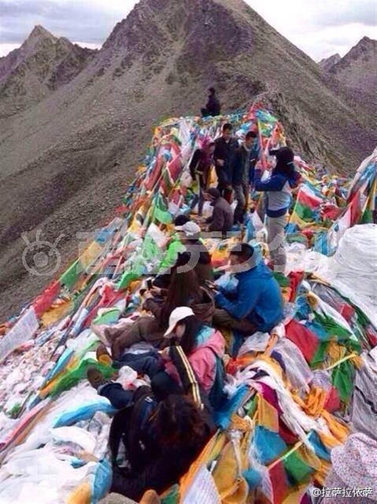 タルチョー（祈祷旗）の上に座ったり、踏みつけたりする漢人旅行者（チベット・ウォッチ提供）