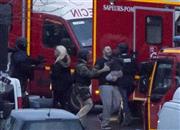 １月９日、首都パリ東部の立てこもり現場で、ユダヤ系食料品店から解放された人質と治安要員。中央の男性は、抱えている３歳の息子と５時間も冷蔵室に隠れて生き延びた＝２０１５年、フランス（ＡＰ）