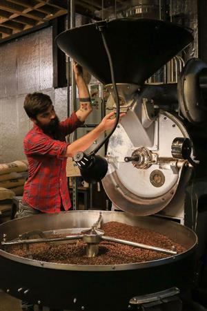 人気コーヒー店「スタンプタウン」の地下で、色や香りを確認しながらコーヒー豆を焙煎するジェシー・ヒューウェイさん。アムステルダムで購入したという１９４２年製の焙煎機は、薄暗い空間に溶け込んでいた＝２０１４年１０月２０日、米ワシントン州シアトル（緑川真実さん撮影）