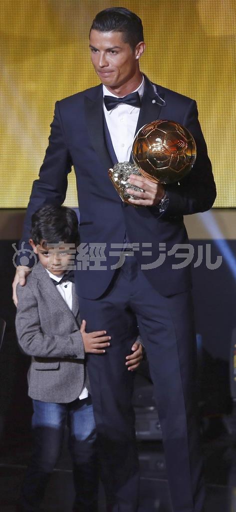 ２年連続３度目のバロンドールを受賞したクリスチアノ・ロナルド。黄金の右足に抱きつき、はにかむのは息子のクリスチアノＪｒ．＝２０１５年１月１２日、オーストリア・チューリヒ（ロイター）