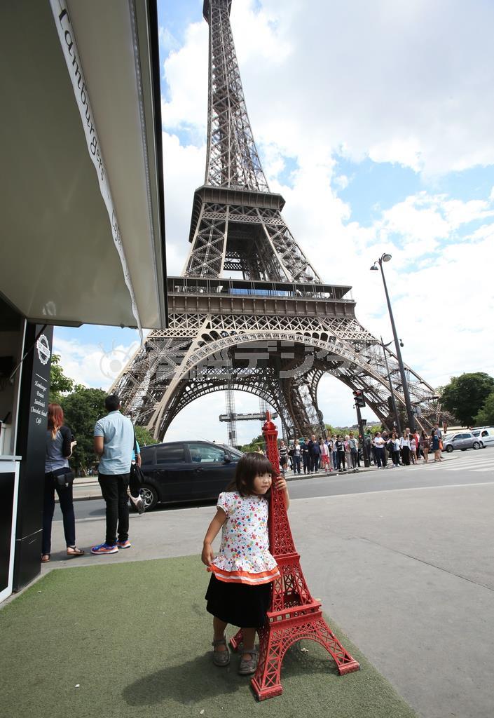屋台のようなお店の前に、小さな赤いエッフェル塔が飾られていました。娘がこれを気に入って抱きかかえた瞬間に撮りました＝２０１４年６月３０日、フランス・首都パリ（須藤夕子さん撮影）