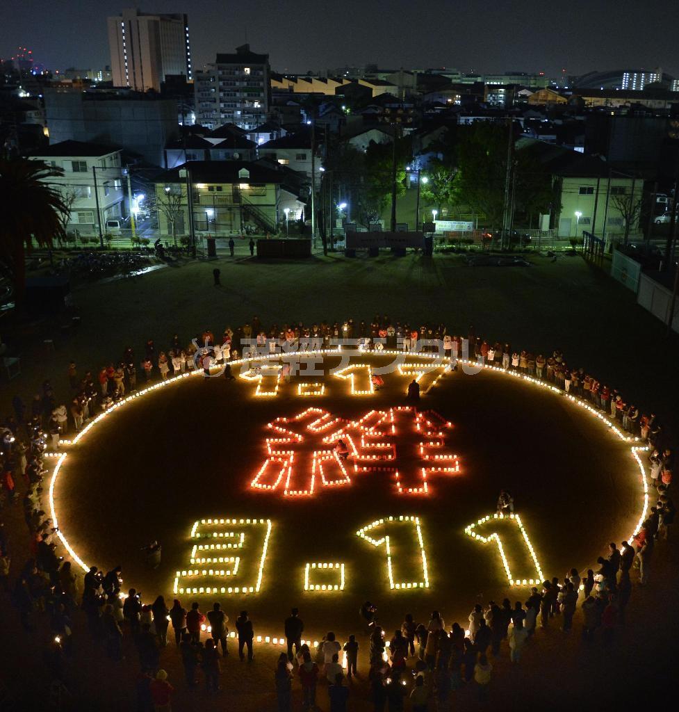 神戸市長田区の市立真野小でともされた東日本大震災の被災地との「絆」を記すろうそくの明かり＝２０１５年１月１７日午前５時４６分、兵庫県（共同）