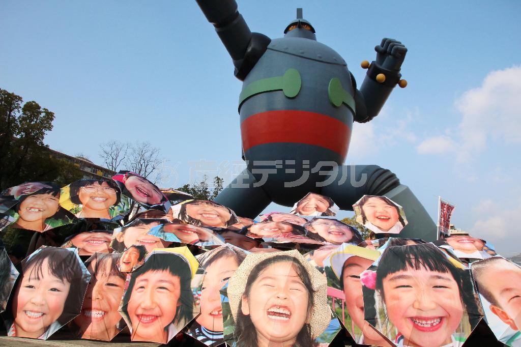 神戸市長田区で復興のシンボル鉄人２８号像の前に並べられた子どもの笑顔がプリントされた傘＝２０１５年１月１７日午前、兵庫県（共同）